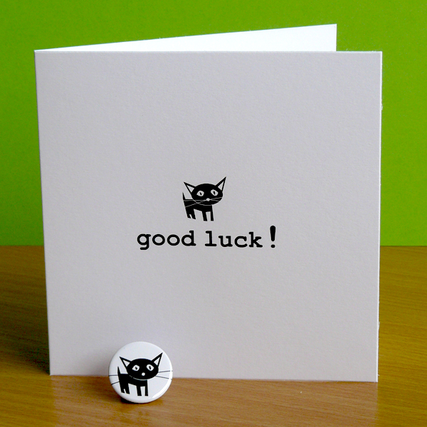 whtie card with black cat and good luck! written and a badge