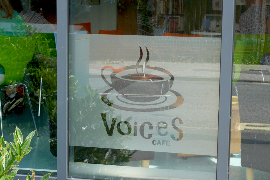 Photograph of window vinyl showing the new Voices Cafe logo